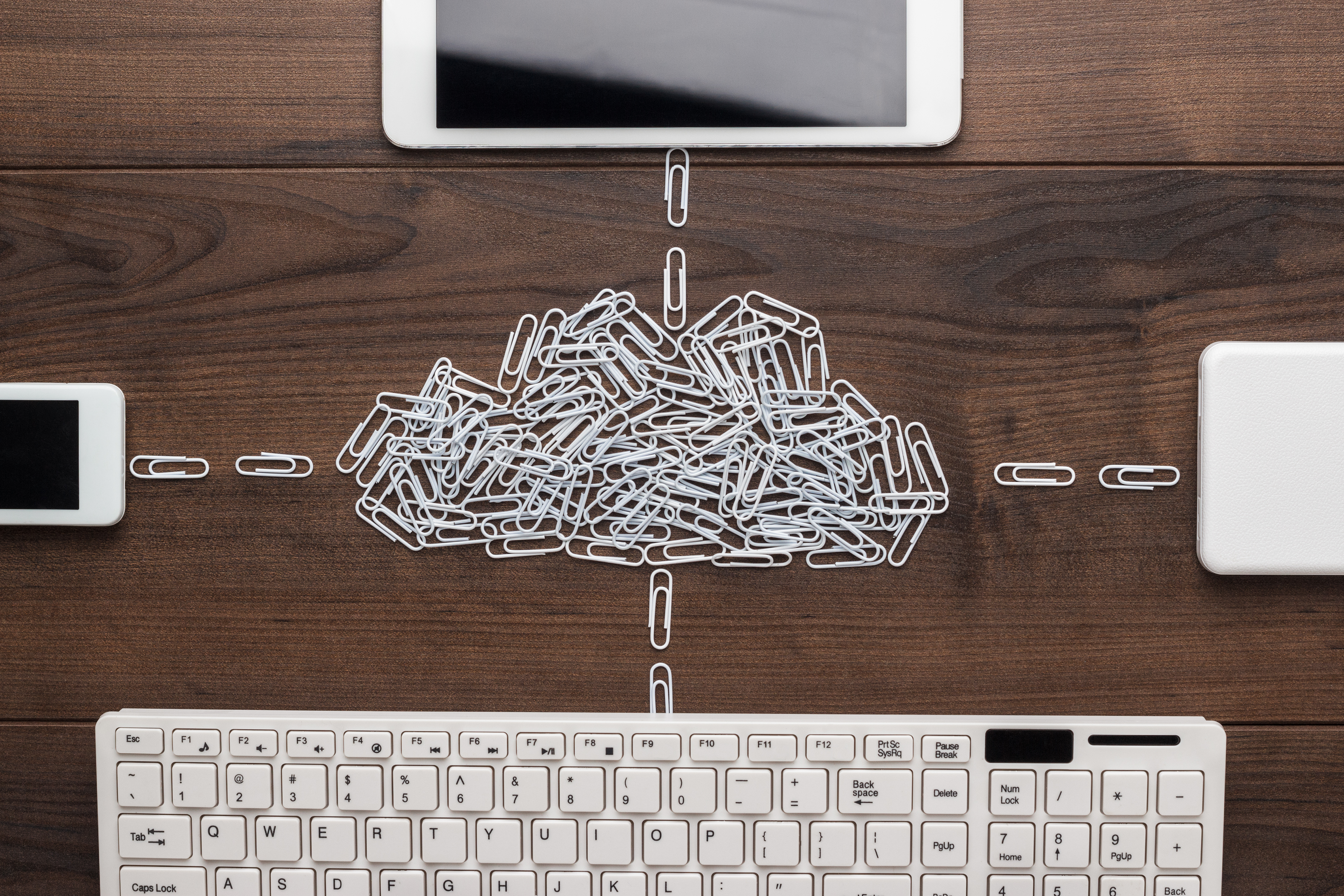 cloud service concept: computer, tablet, phone, hard drive connected to the cloud made of white paper clips